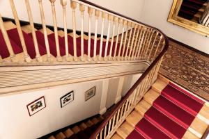 a staircase with wooden treads and a red striped carpet at Schloss Burgellern in Scheßlitz