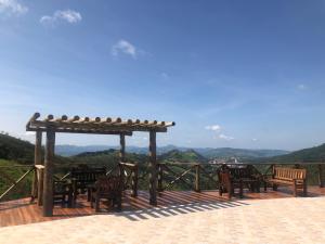 una terraza de madera con sillas y pérgola en Fazenda Morro Pelado, en Águas de Lindóia