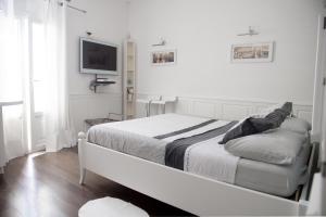 um quarto branco com uma cama e uma televisão de ecrã plano em Casa San Vito em Monopoli