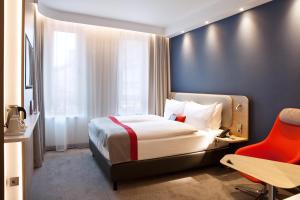 une chambre d'hôtel avec un lit et un fauteuil rouge dans l'établissement Holiday Inn Express - Darmstadt, an IHG Hotel, à Darmstadt