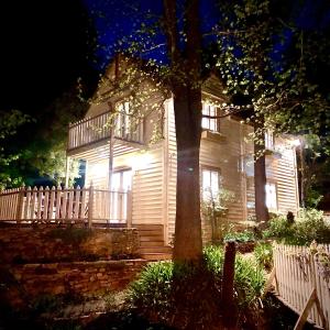 Aldgate Creek Cottage Bed and Breakfast في Aldgate: بيت ابيض فيه شرفه وشجر بالليل