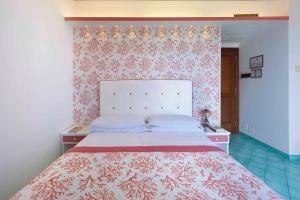 1 dormitorio con 1 cama con colcha roja y blanca en Hotel Girasole, en Sorrento