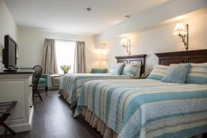 a hotel room with two beds and a television at The Village Inn of Lakefield in Lakefield