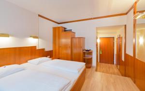 1 Schlafzimmer mit 2 weißen Betten und Holzmöbeln in der Unterkunft Vienna Sporthotel in Wien