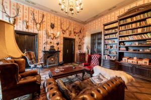 a living room with leather furniture and bookshelves at Burbiskio dvaras in Anykščiai