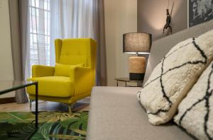 - un salon avec un fauteuil jaune et un canapé dans l'établissement DE LA GUARDIA SUITE 1, à Oviedo