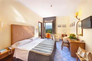 Dormitorio con cama, escritorio y TV en Hotel Girasole, en Sorrento