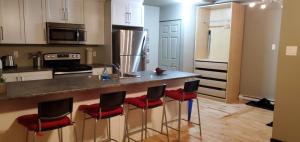 een keuken met een aanrecht met rode barkrukken bij 1-Bedroom Apartment Bellisimo AG by Amazing Property Rentals in Gatineau