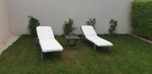 twee witte stoelen en een tafel in het gras bij clos des mûriers in Beaune