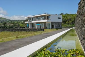 卡佩拉什São Vicente Lodge - Panoramic Retreat的山丘上的房子,前面有一个池塘