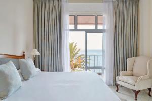 ein Schlafzimmer mit einem großen Bett und einem Fenster mit Meerblick in der Unterkunft Reid's Palace, A Belmond Hotel, Madeira in Funchal