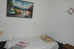 ein Schlafzimmer mit einem weißen Bett und einem Gemälde an der Wand in der Unterkunft Hostal Nicaragua Guest House in Managua