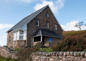 una vecchia casa di mattoni con un muro di pietra di Gairloch Sands Youth Hostel a Gairloch