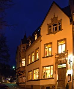 Un grand bâtiment blanc avec des fenêtres éclairées la nuit dans l'établissement Parkschlösschen in Greiz, à Greiz