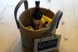 a basket with a bottle of wine and a sign at vakantiehuis op de veluwe in Wolfheze