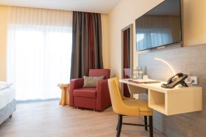 a hotel room with a desk and a red chair at Mythenresort Heimdall in Thale