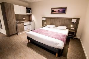 Tulip Inn Thionville Residences في تيونفيل: غرفه فندقيه بسرير ومطبخ