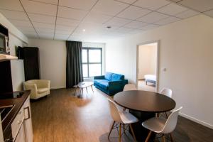 Tulip Inn Thionville Residences في تيونفيل: غرفة معيشة مع طاولة وأريكة زرقاء