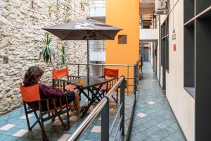 a woman sitting at a table with an umbrella at Granados Hostel in Buenos Aires