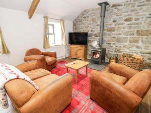 ein Wohnzimmer mit Ledermöbeln und einer Steinmauer in der Unterkunft Rhydau Cottage in Bangor