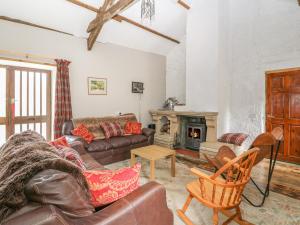 een woonkamer met lederen meubels en een open haard bij Felin Iago in Aberystwyth