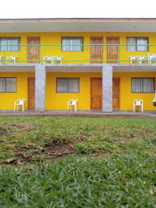 un bâtiment jaune avec des chaises blanches devant lui dans l'établissement Hotel San Juan, à Coquimbo