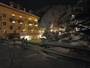 ein Hotel in der Nacht mit einem Weihnachtsbaum und einem Zaun in der Unterkunft Le Miramonti Hotel Restaurant & Wellness in La Thuile