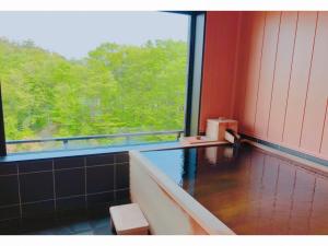 a room with a bath tub and a large window at Kajitsu no Mori in Ichinoseki