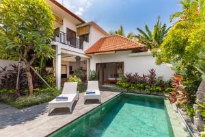 eine Villa mit einem Pool, 2 Stühlen und einem Haus in der Unterkunft Sawah Villas in Ubud