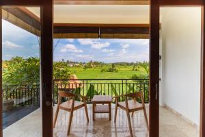 einen Blick vom Balkon eines Hauses mit einem Tisch und Stühlen in der Unterkunft Sawah Villas in Ubud