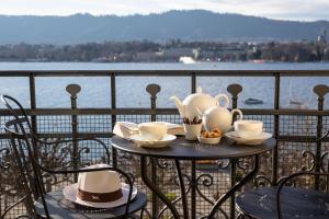 een tafel met kopjes en theepotten op een balkon bij La Réserve Eden au Lac Zurich in Zürich