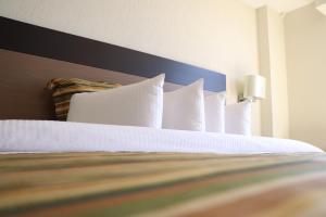 um quarto com uma cama com almofadas brancas em Ramada Hola Culiacan em Culiacán