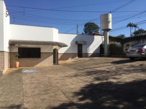 ein weißes Gebäude mit einem Auto auf einem Parkplatz in der Unterkunft Hotel Taquaral in Campinas