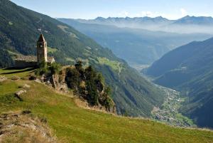 una iglesia en una colina con vistas a un valle en Ca' del Borgo, Rooms & Suites, en Poschiavo