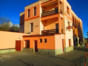 un edificio naranja y blanco con aparcamiento en Penzion Partizan, en Vysoke Tatry - Horny Smokovec