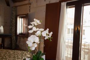 een vaas met witte bloemen op een tafel naast een raam bij Hotel Boa Vila in Pontevedra