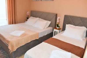 2 Betten in einem Hotelzimmer mit Blumen in der Unterkunft Beach Walk Apartments in Ulcinj