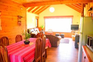 uma sala de jantar com uma mesa e uma sala de estar em Cabaña Caburgua Hermosa vista al Volcán, Senderos del Bosque em Pucón