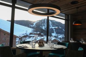 uma sala de jantar com uma mesa e uma grande janela em Hôtel Prestige Odalys Le Chamois em La Clusaz