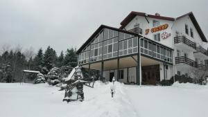 um grande edifício com neve em frente em Guest House U Sester em Skhidnitsa