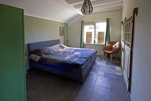 1 dormitorio con 1 cama, 1 silla y 1 ventana en Het Jachthuus - Vakantiewoning Oscar Hoeve, en Ede