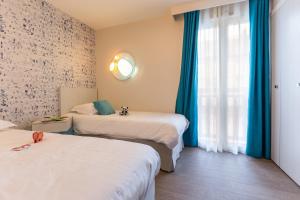 een hotelkamer met 2 bedden en een raam bij Résidence Pierre & Vacances Premium Presqu'Ile de la Touques in Deauville