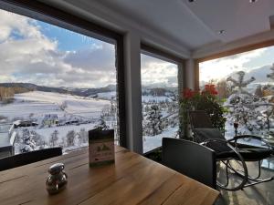 una stanza con tavolo e una grande finestra con neve di Jaworki Green Dream a Szczawnica