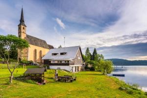 une église assise à côté d'une nappe d'eau dans l'établissement Marvelous lake view apartments - Jezerka Lipno, à Přední Výtoň