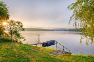 un petit bateau assis sur le côté d'un lac dans l'établissement Marvelous lake view apartments - Jezerka Lipno, à Přední Výtoň