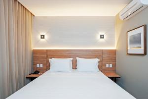 a bedroom with a large white bed with two pillows at Slaviero Curitiba Aeroporto in São José dos Pinhais