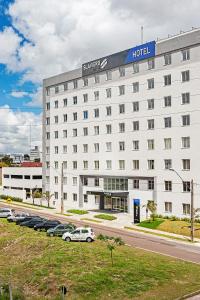 a white hotel with cars parked in front of it at Slaviero Curitiba Aeroporto in São José dos Pinhais