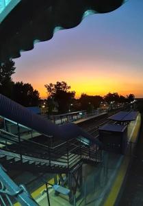 a sunset at a train station with a train pulling into the station at Aloha III - El Palomar B&D in El Palomar