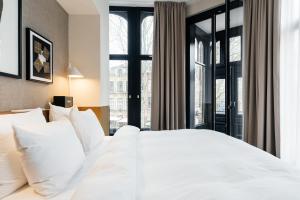 a bedroom with a large white bed with windows at The Hunfeld in Utrecht