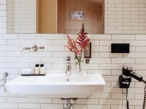 - un lavabo blanc dans la salle de bains avec un vase de fleurs dans l'établissement Pokoje Gościnne WIDNOKRĄG, à Sandomierz